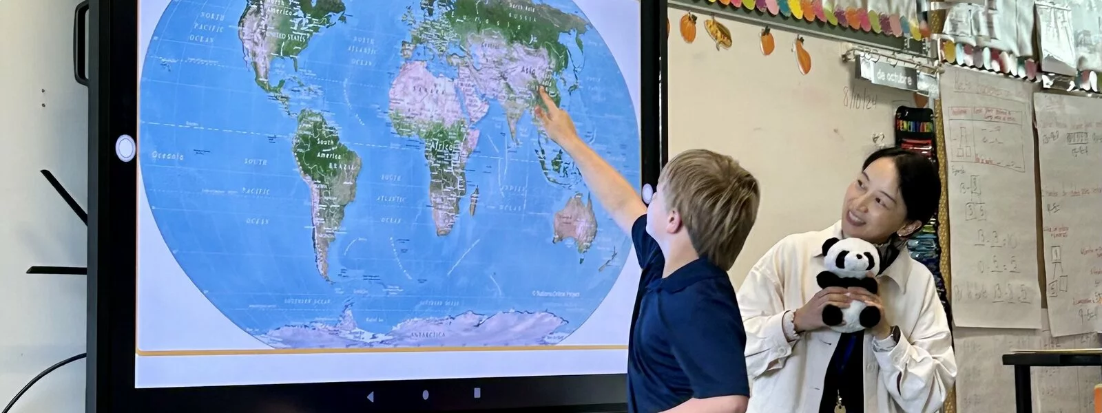 student and teacher looking at world map