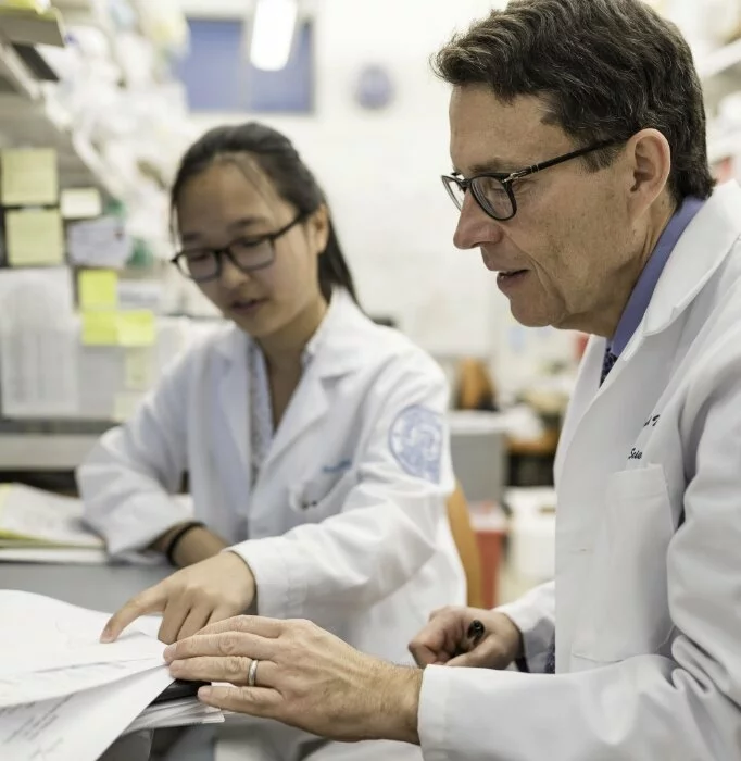 Two scientists sit together reviewing papers