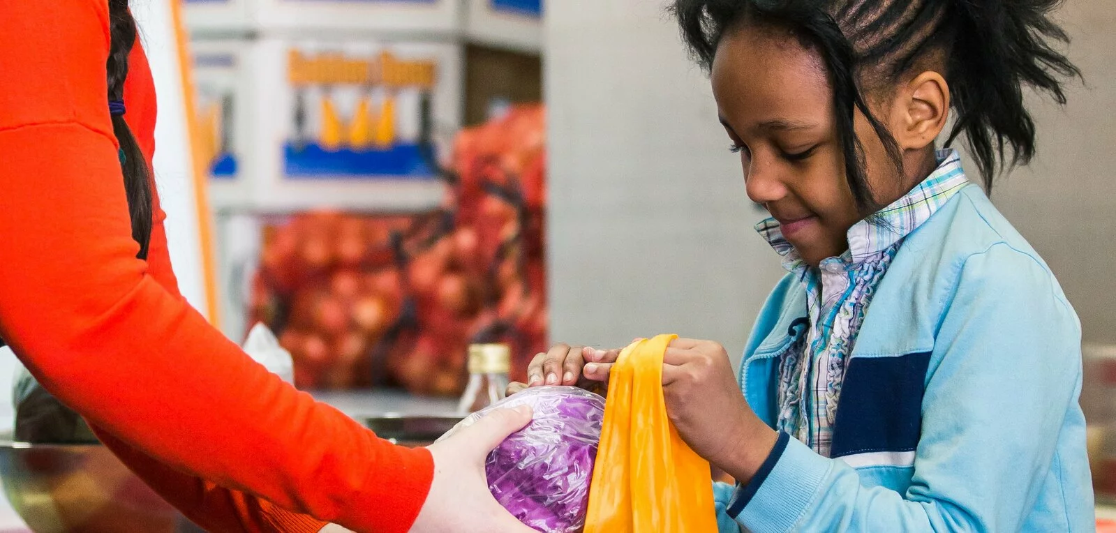 Woman helps fill the shopping bag of a young girl.