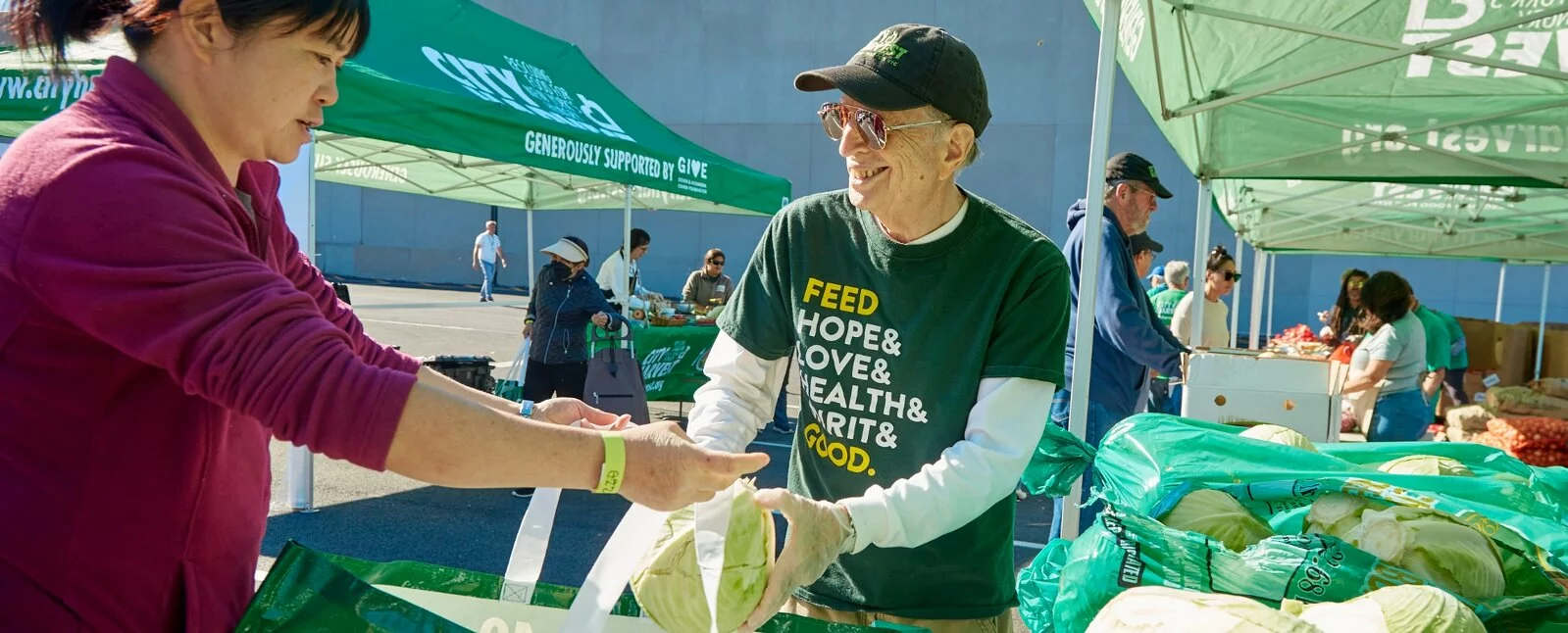 A man and woman load food into a City Harvest shopping bag