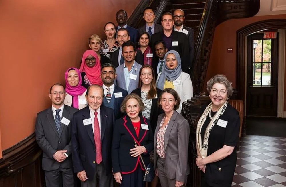 Lined up on a staircase, Mr. Greenberg, Mrs. Corinne Greenberg, and former President of The Starr Foundation Ms. Florence Davis with the Greenberg World Fellows at Yale University.