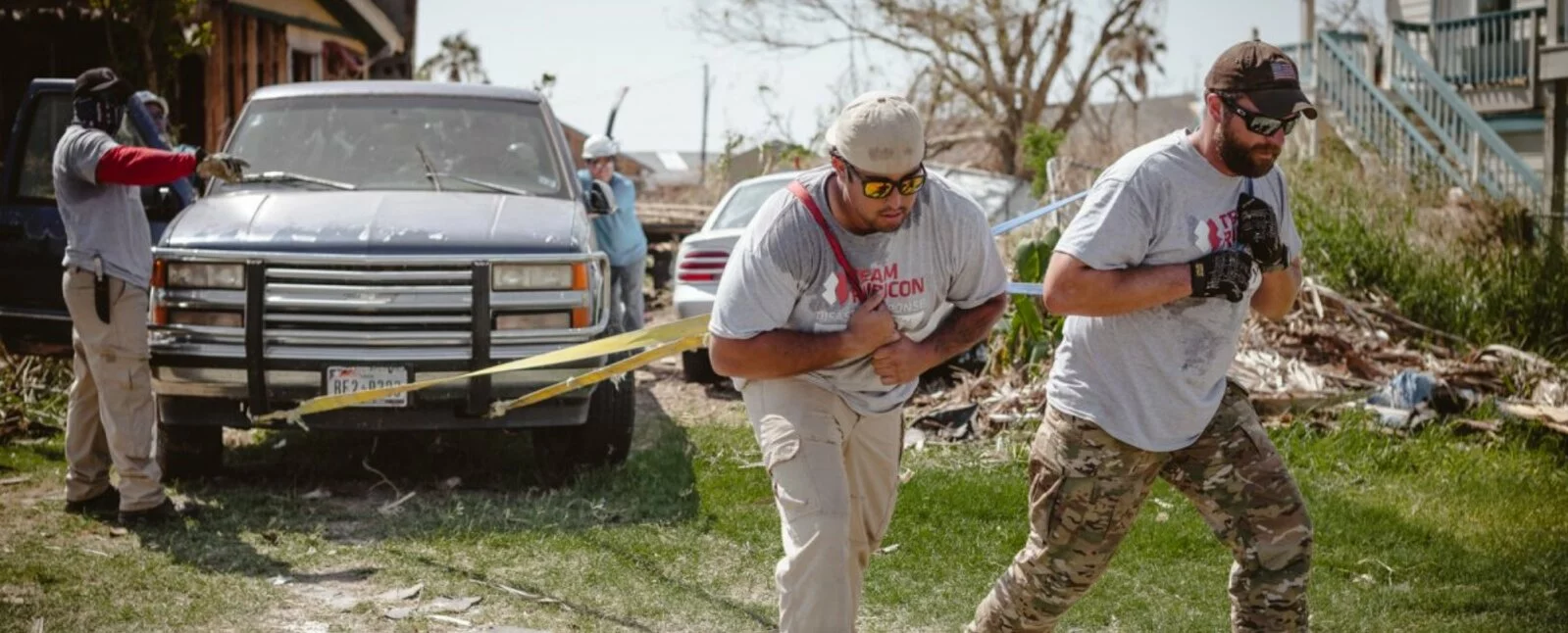 Two men work together to pull a truck