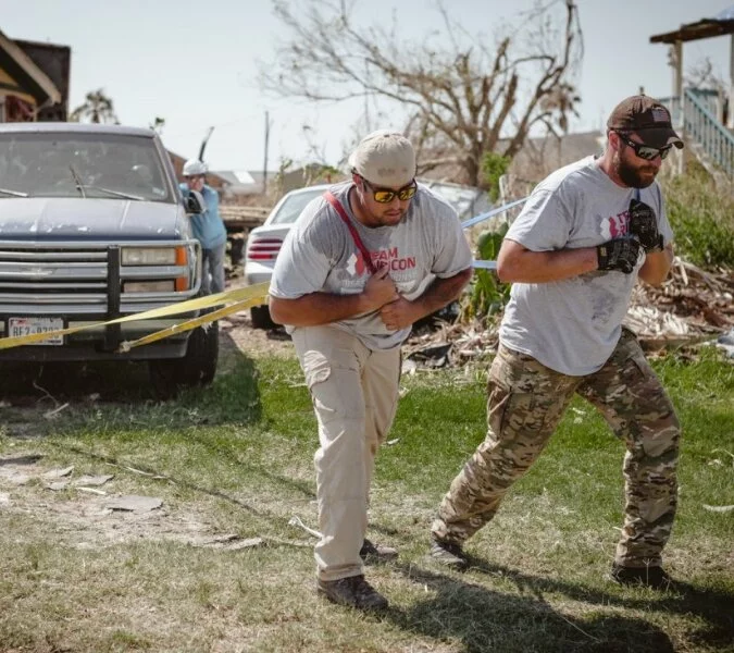 Two men work together to pull a truck