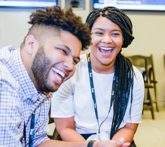 Two students sit together in a classroom laughing.