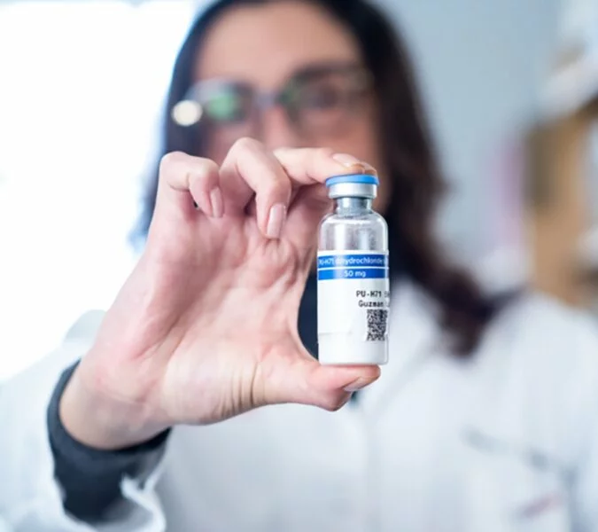 A scientist holds a glass vial