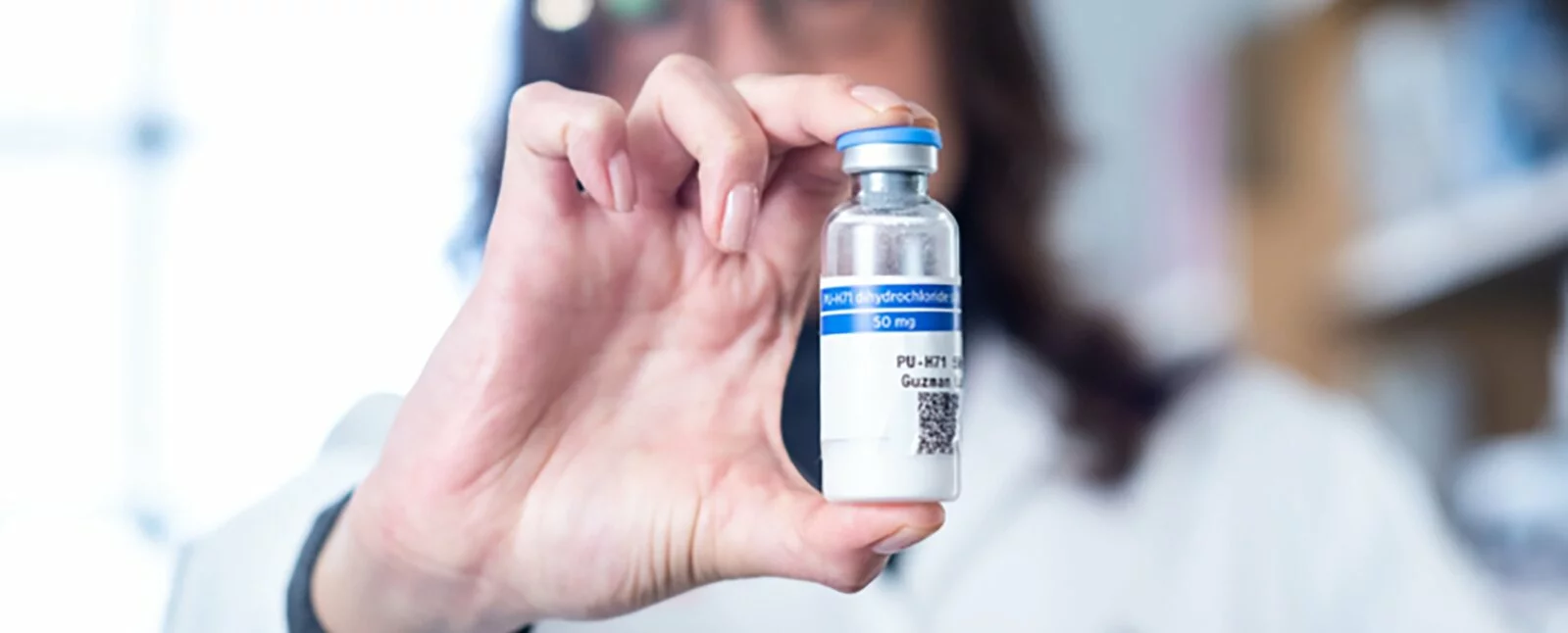 A scientist holds a glass vial