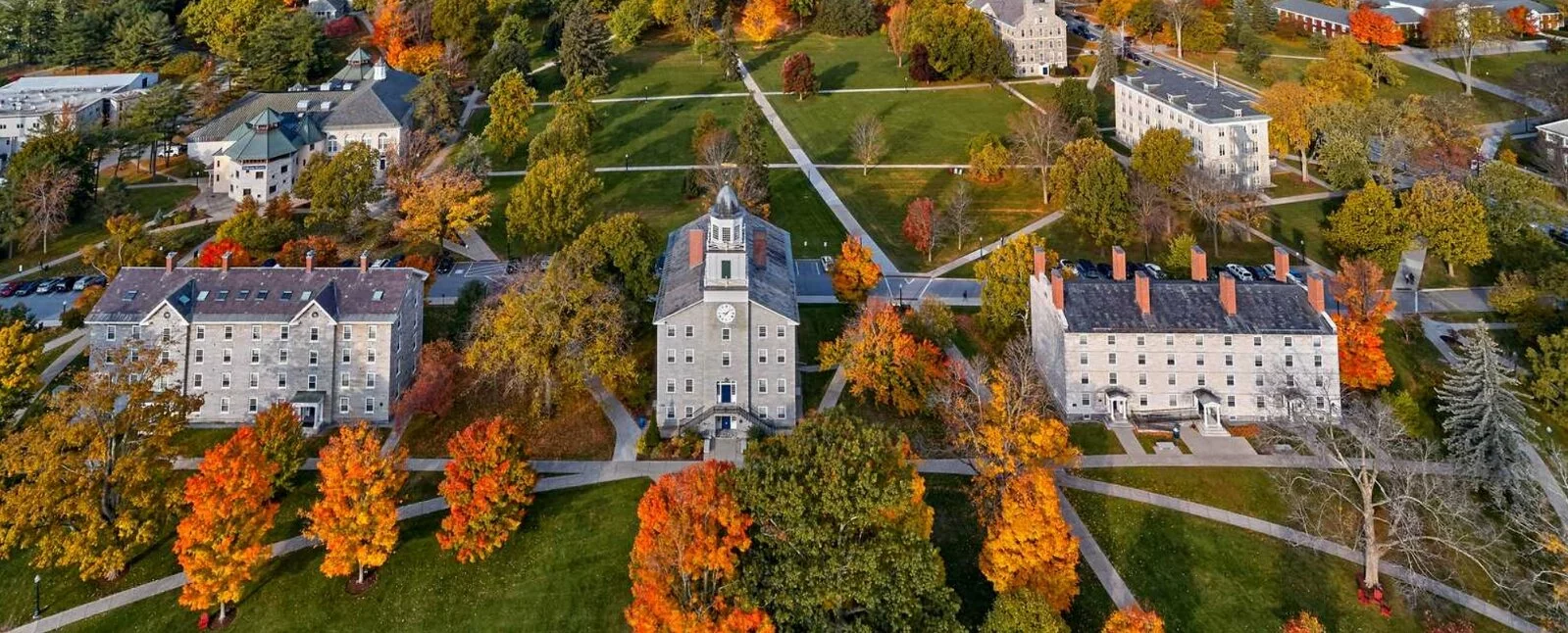 An aerial view of the Middlebury College campus featuring autumn colors - bright orange, yellow, and green trees.